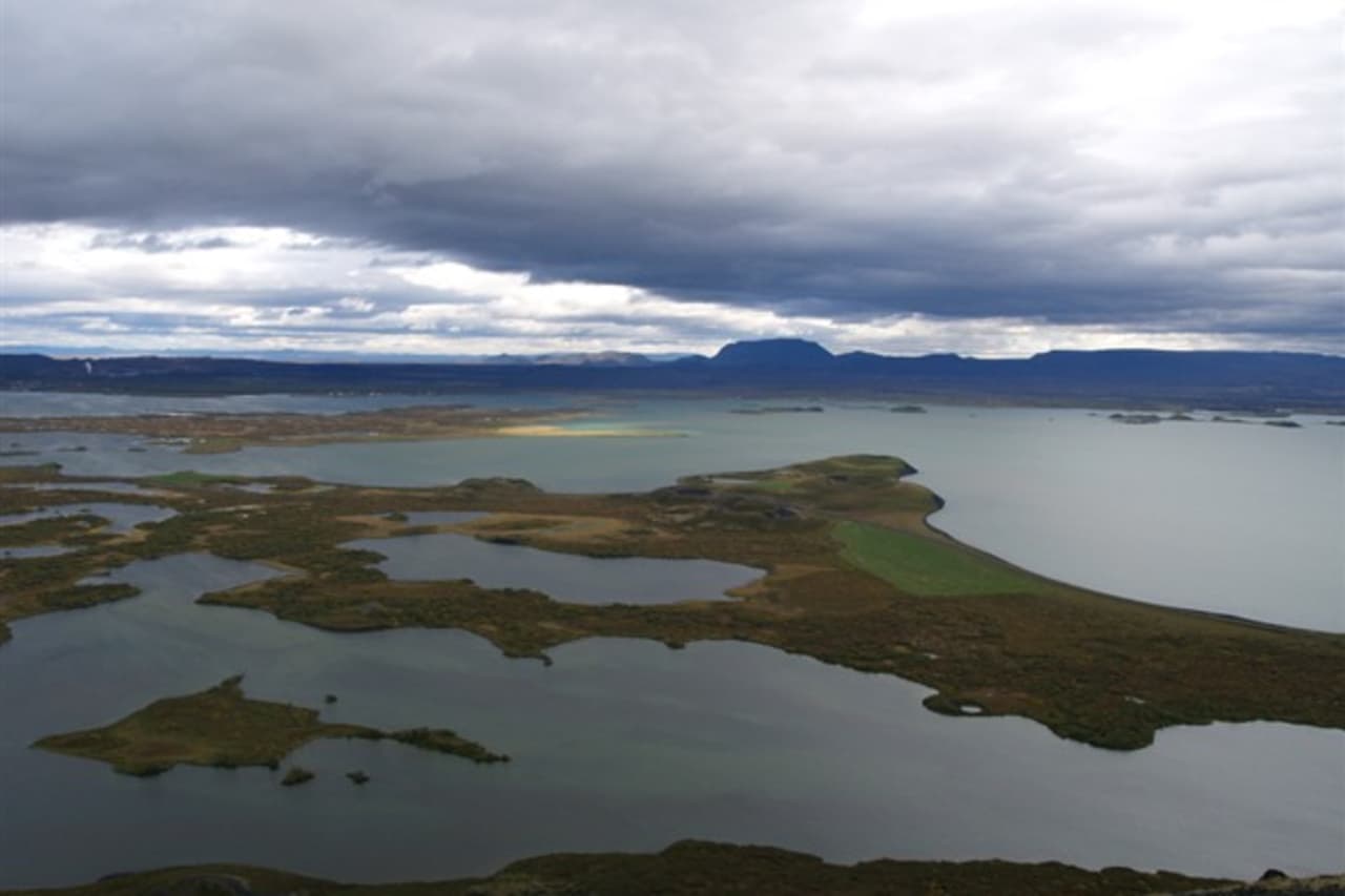 Wide view over Lake Mývatn wetlands and Skútustaðagígar pseudocraters under low North Iceland cloud.