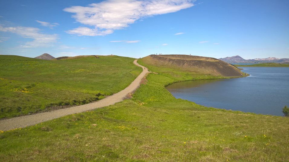 Marked gravel path curving through green Skútustaðagígar pseudocraters beside Lake Mývatn.