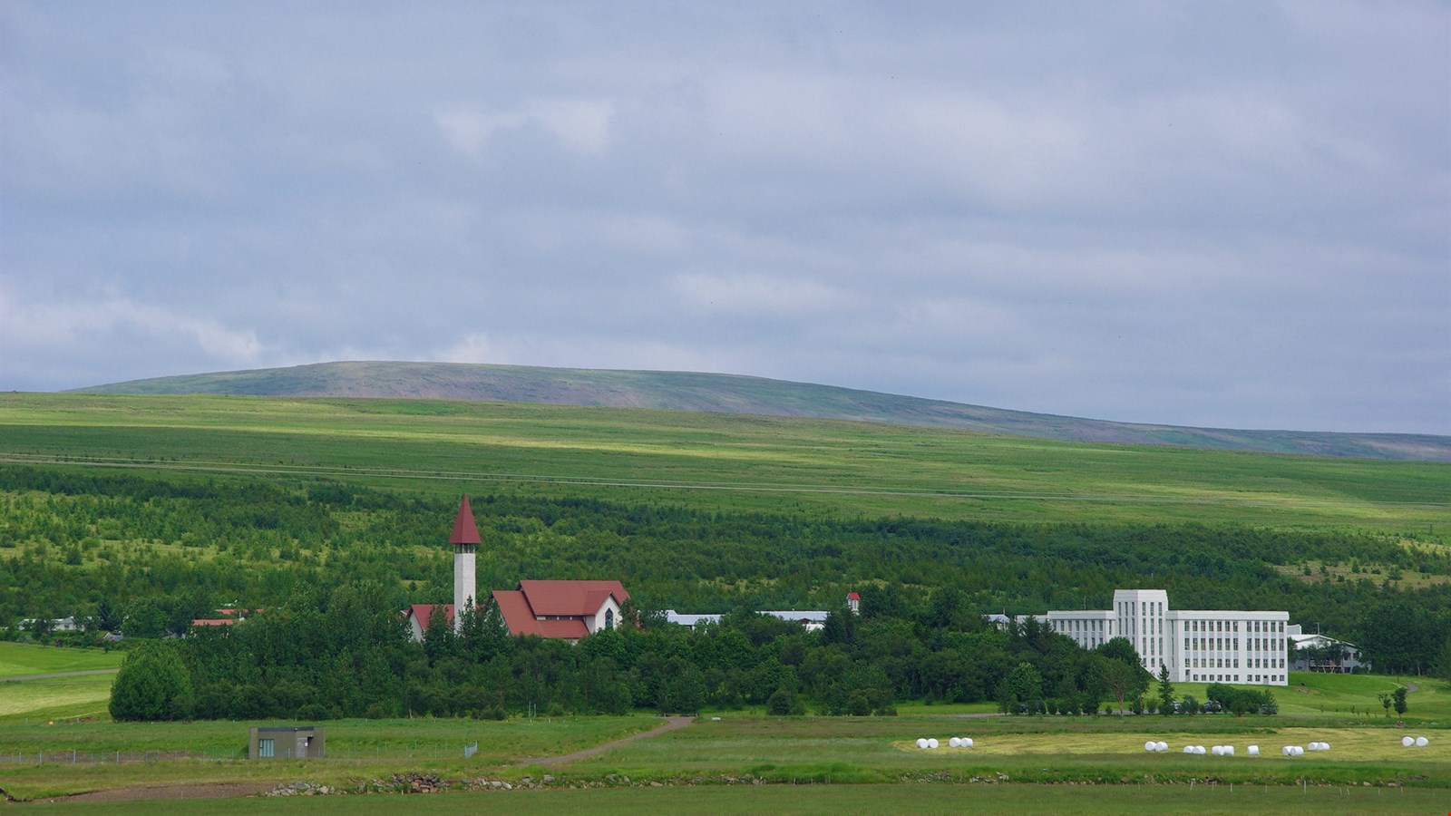 Snorrastofa and Reykholt church buildings on a green hill in West Iceland.