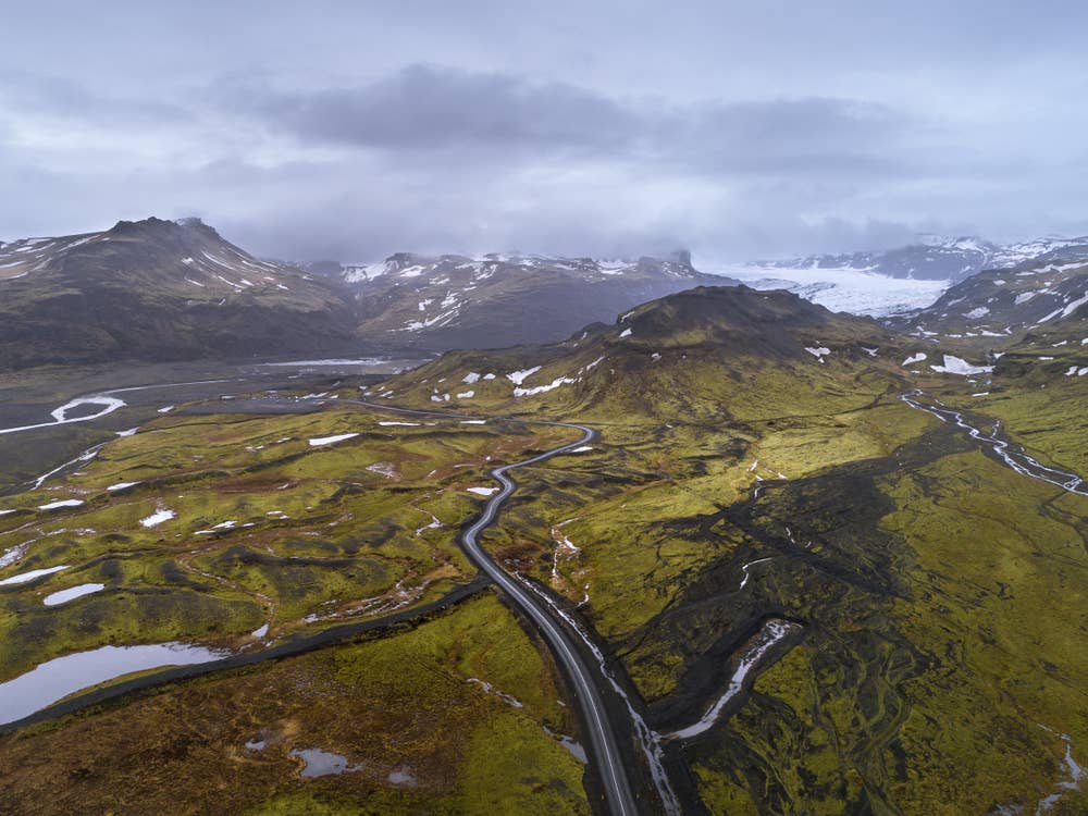 Road approach toward Sólheimajökull Glacier through green and black volcanic terrain