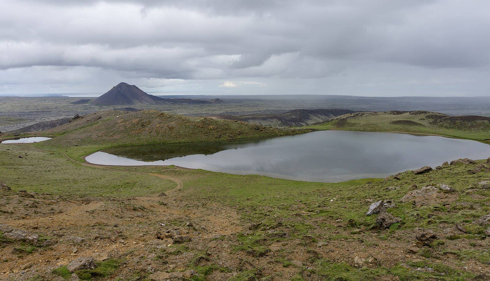 Spákonuvatn crater lake below rough Reykjanes ridges with Keilir visible beyond the lava fields.