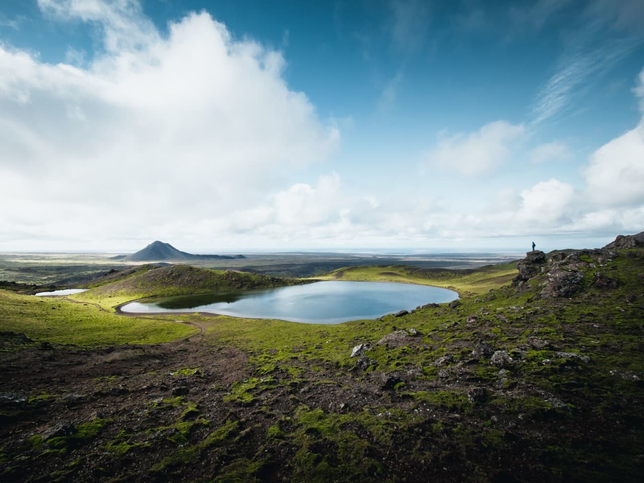 Spákonuvatn crater lake in the Reykjanes volcanic hills with lava fields and sky beyond.