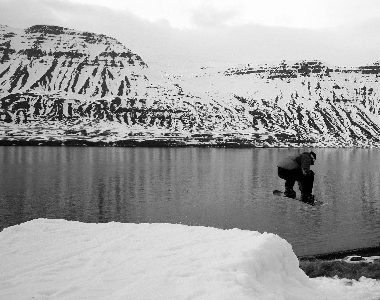 Snowboarder beside the snowy Seyðisfjörður fjord in East Iceland.