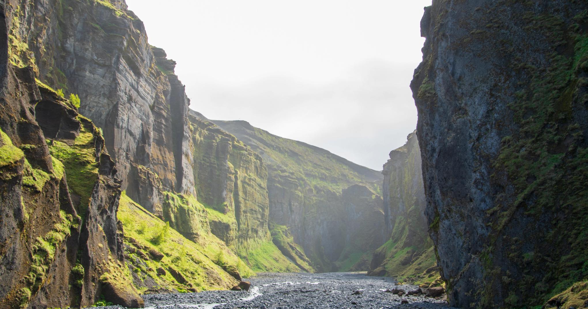 Stakkholtsgjá canyon with a shallow river running between steep mossy rock walls.