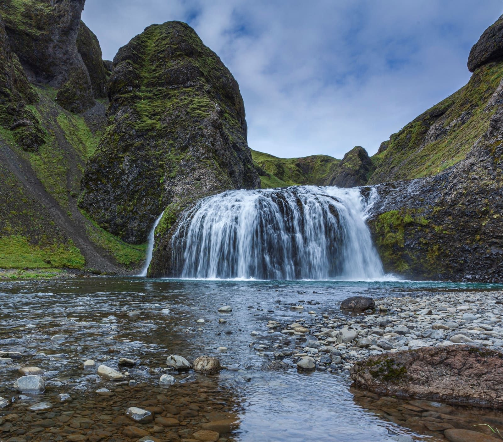 Stjórnarfoss waterfall dropping into a rocky pool beneath steep mossy walls near Kirkjubæjarklaustur.