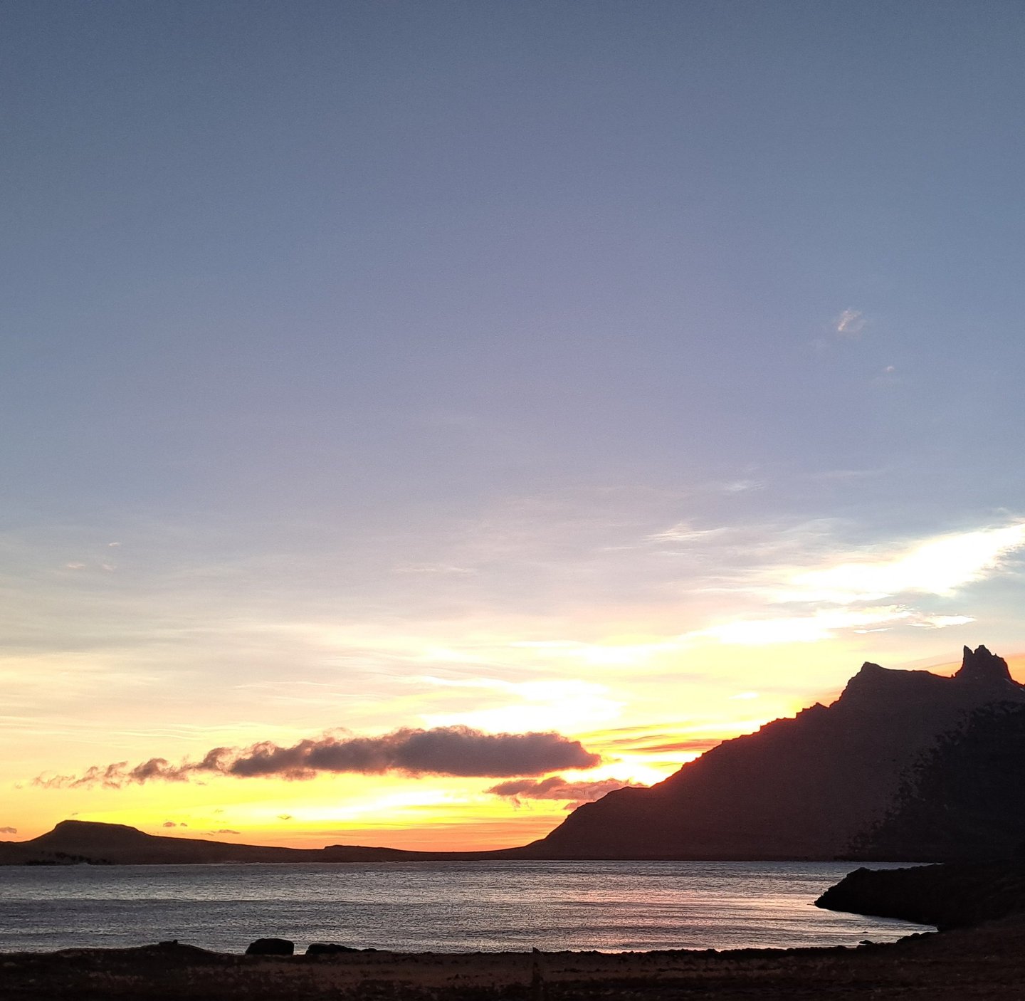 Sunset over the bay at Stöðvarfjörður with the village mountain silhouette dark against the evening sky.