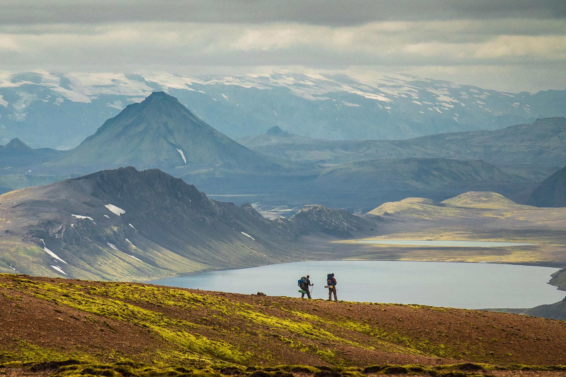 Backpackers on the Laugavegur Trail above Álftavatn with highland mountains beyond.