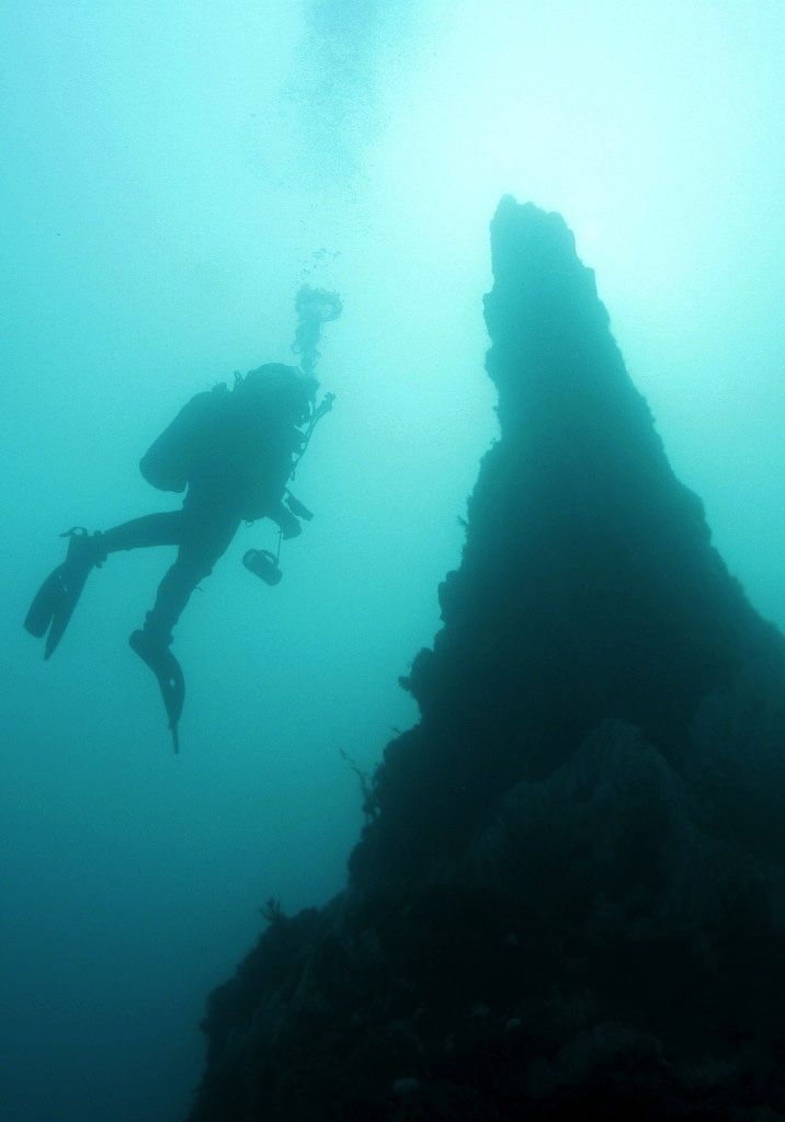 A diver moving beside the contours of a Strýtur underwater geothermal chimney.