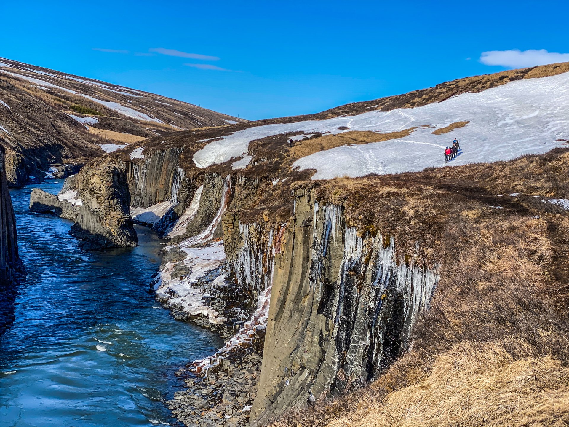 Wide view of Stuðlagil Canyon with a blue river running between dark basalt walls in East Iceland.