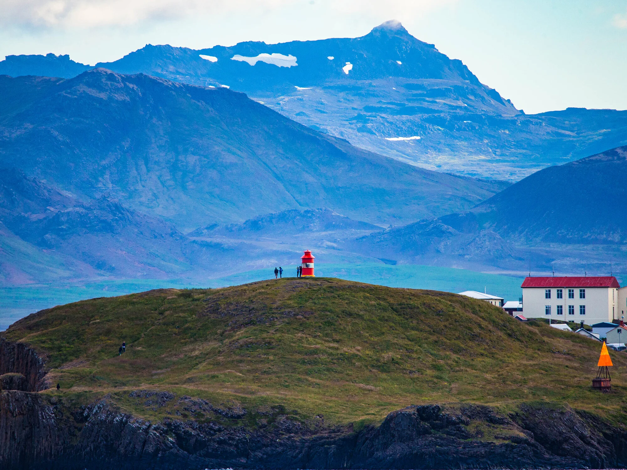 Súgandisey lighthouse seen against blue mountains above the Stykkishólmur harbor area.