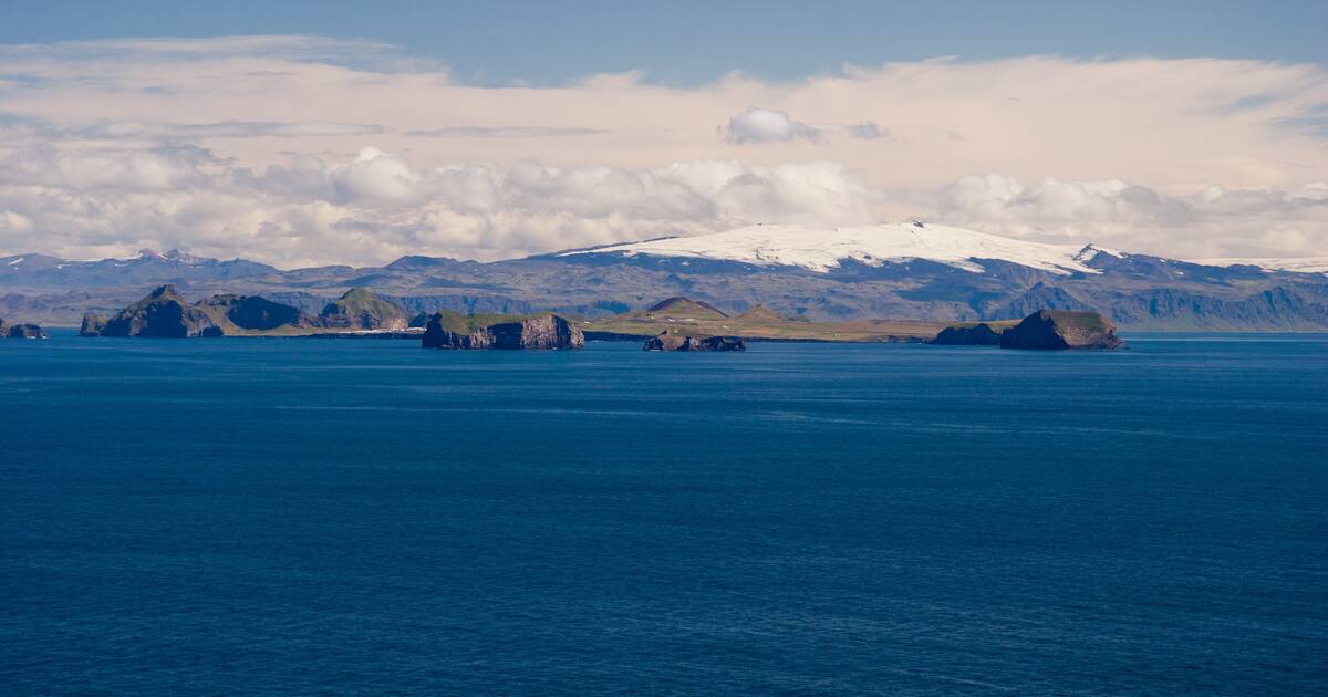 Surtsey appearing as a low dark island beyond open blue sea.