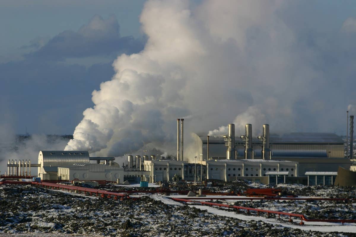 Close view of Svartsengi Power Station buildings, steam, pipes, and dark lava ground.