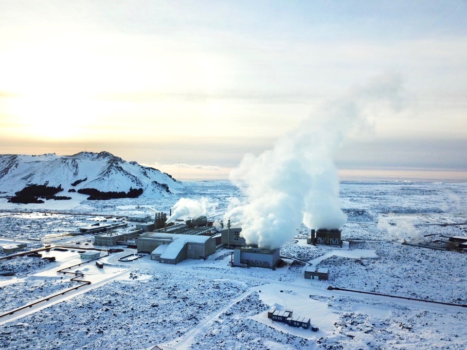 Steam rising from Svartsengi Power Station in a snowy Reykjanes lava field below low volcanic hills.
