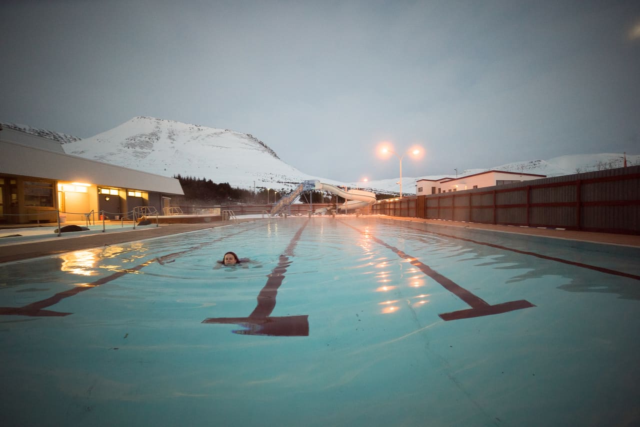 Outdoor pool in Tálknafjörður with snowy Westfjords mountains behind the village.