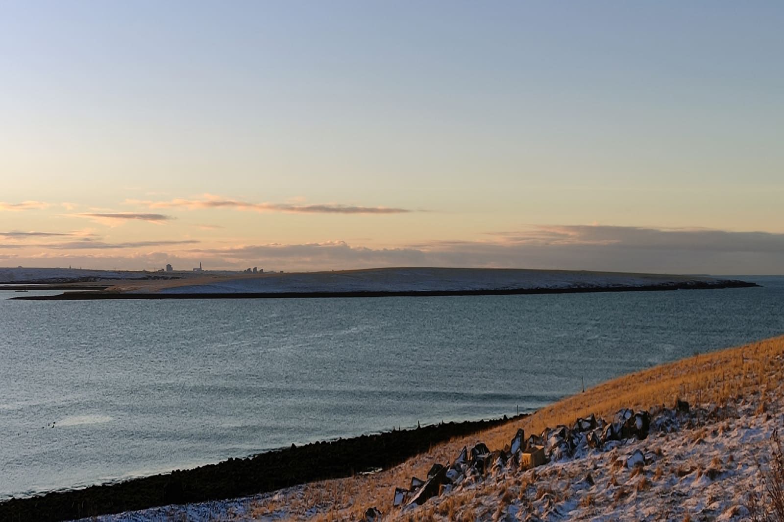 Þerney island and the Kollafjörður shoreline seen across winter-blue water near Reykjavík.
