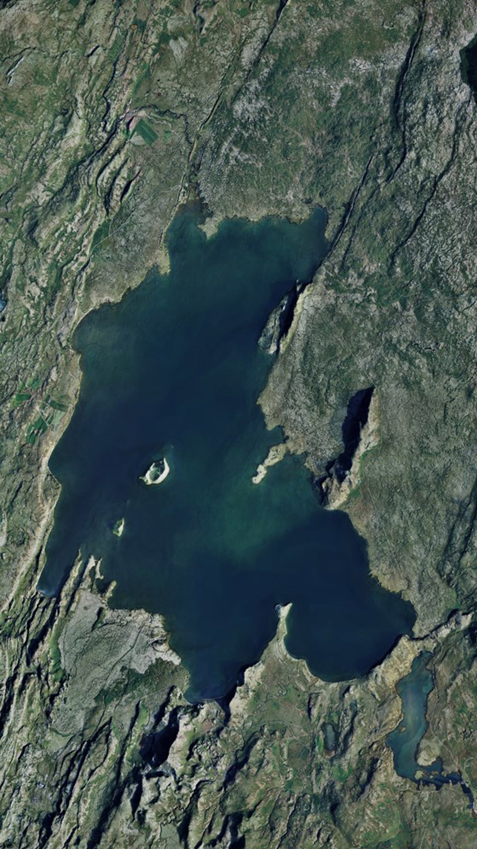 Aerial view of Lake Þingvallavatn surrounded by rift lines, lava terrain, and smaller water bodies.