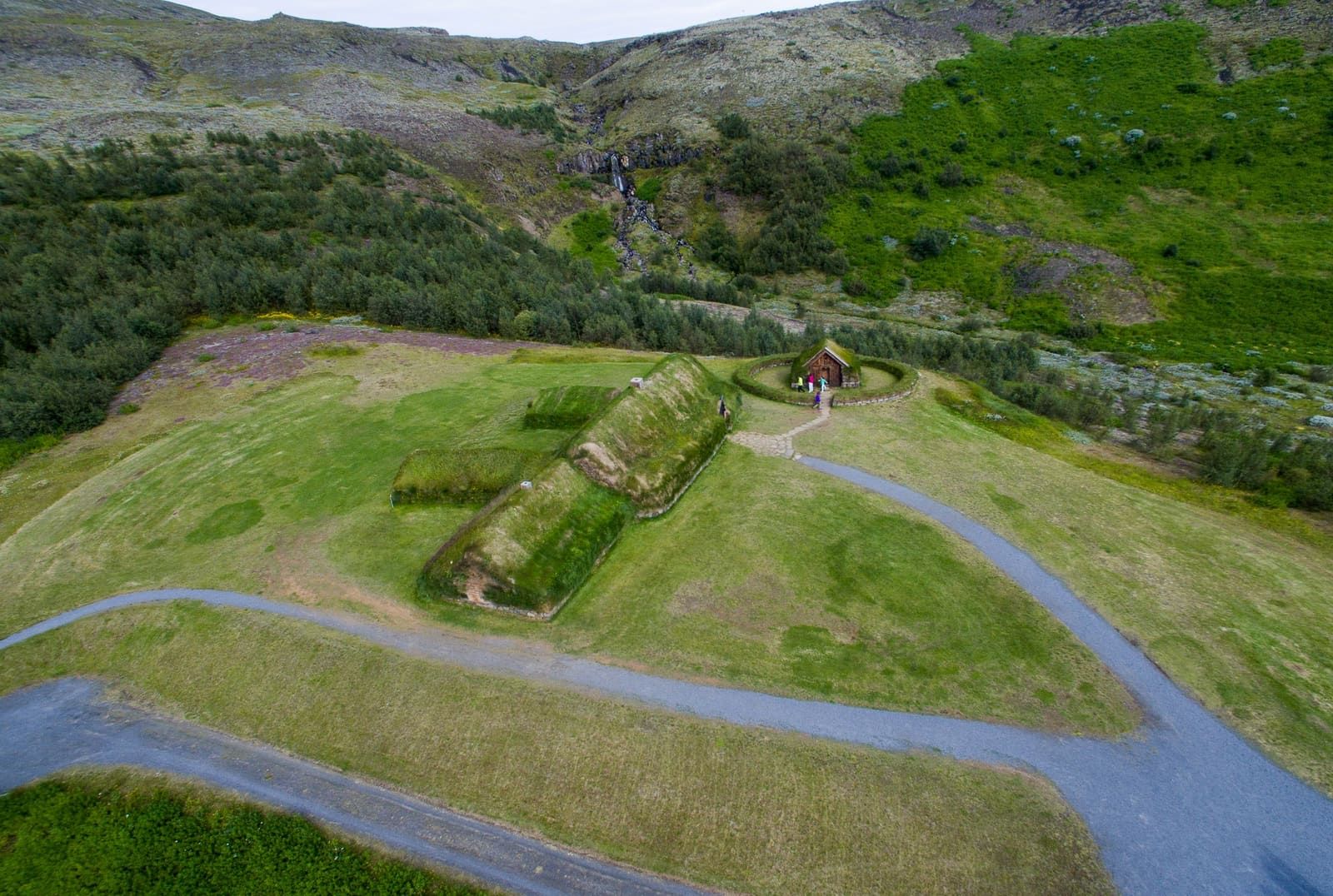 Aerial view of Þjóðveldisbærinn at Stöng with turf buildings, paths, and green Þjórsárdalur hills.