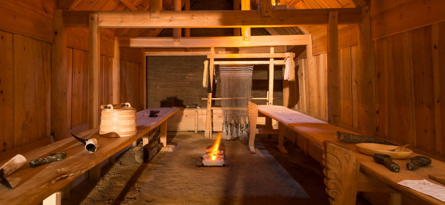 Wooden interior of Þjóðveldisbærinn with benches, a loom, and a central hearth.