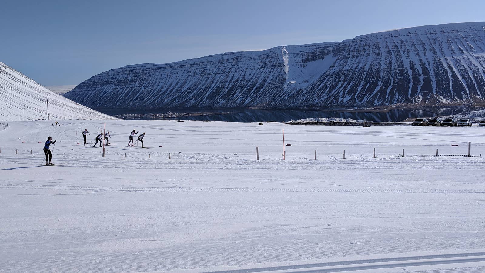 Skiers and parked cars in snowy Seljalandsdalur below steep Westfjords mountains near Þjófatindar.