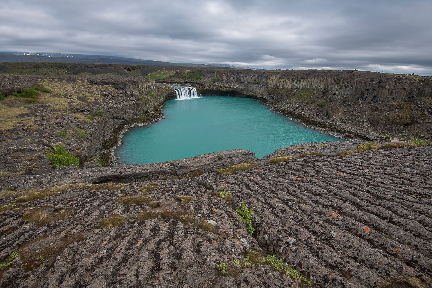 Þjófafoss waterfall dropping into a blue-green pool among dark lava rock in the Þjórsá river.