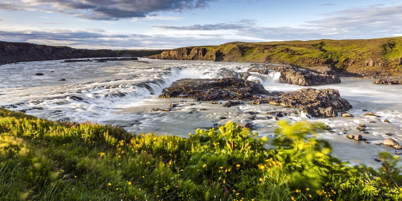 Urriðafoss waterfall spreading across the Þjórsá river with dark rock and green riverbank in South Iceland.