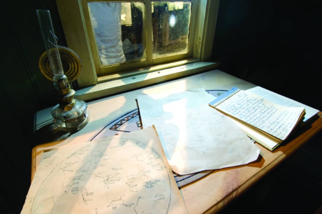 Desk display with handwritten pages, maps, and an old lamp inside Þórbergssetur.