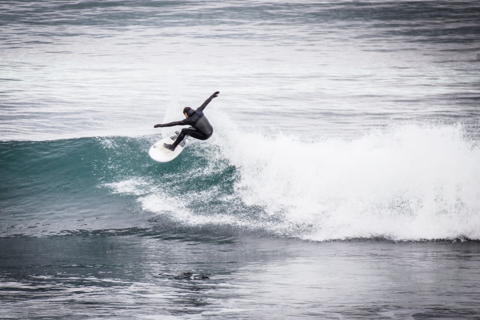 A surfer riding a wave off the coast at Þorlákshöfn.