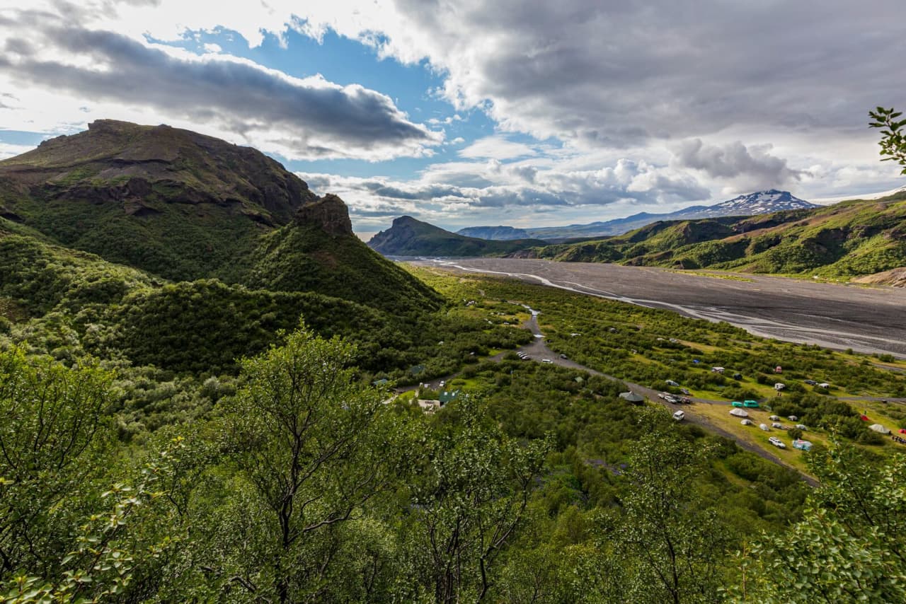 Þórsmörk valley with birch slopes, huts, braided riverbed, and mountains in the Icelandic Highlands.