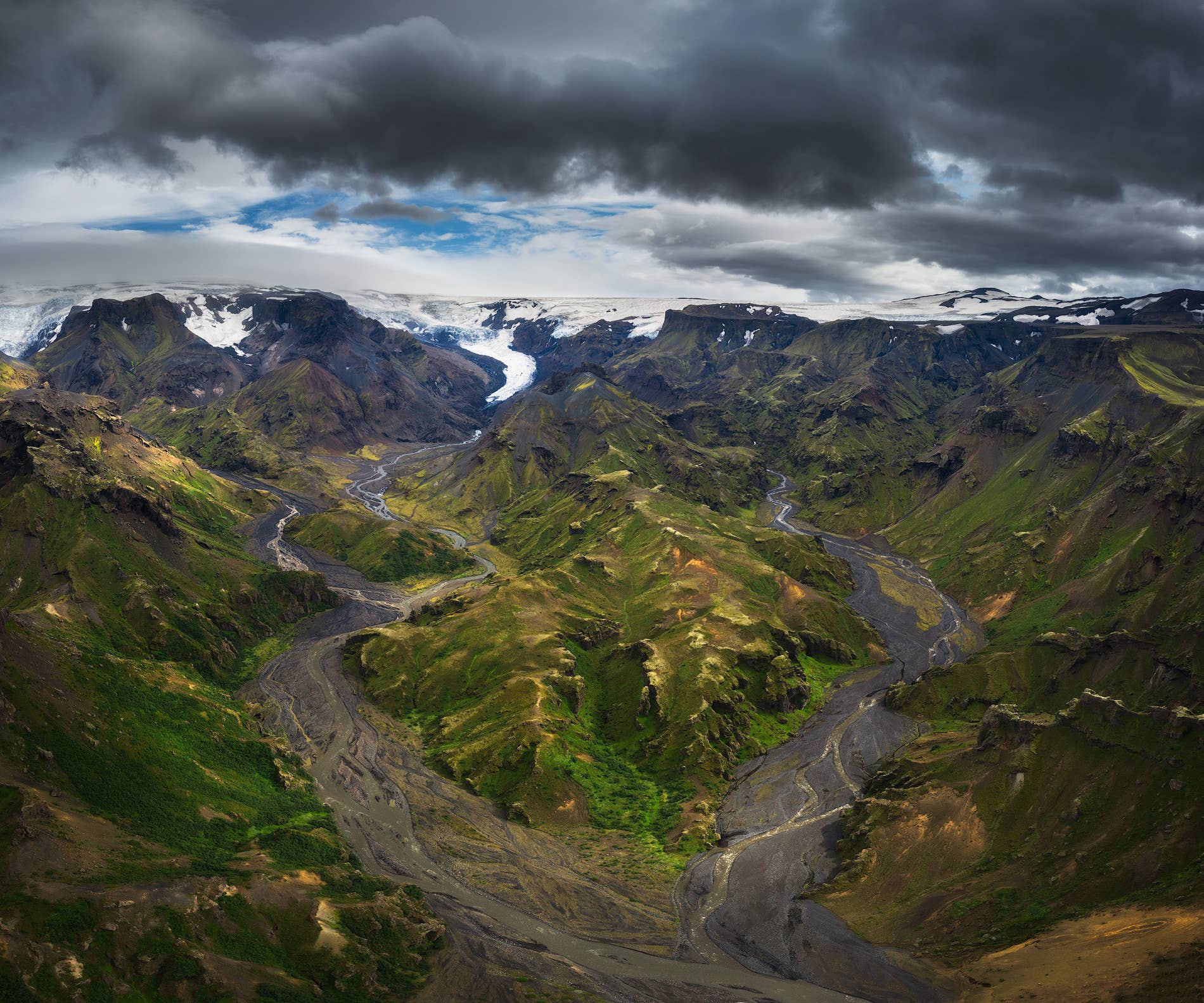 Wide Þórsmörk view with braided rivers, green mountains, glaciers, and dark clouds.