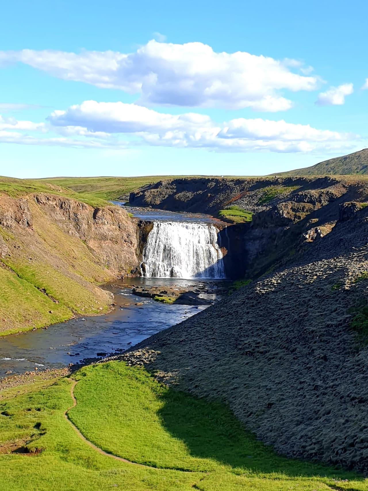 Þórufoss dropping into a green canyon with the Laxá í Kjós flowing away below.
