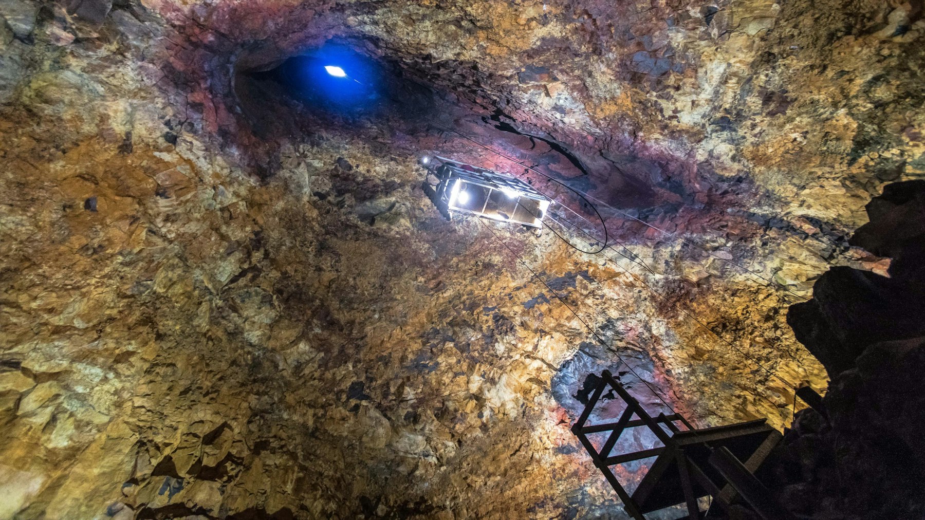 Open lift hanging high inside Þríhnúkagígur with the crater opening visible above.