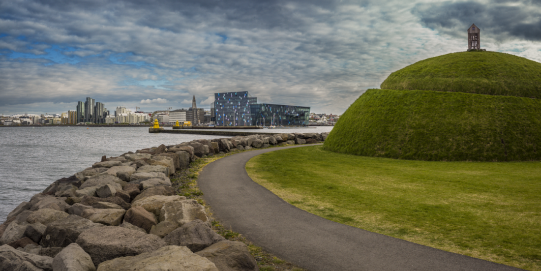 Þúfa's grassy harbour mound and winding path with Harpa and Reykjavík across the water