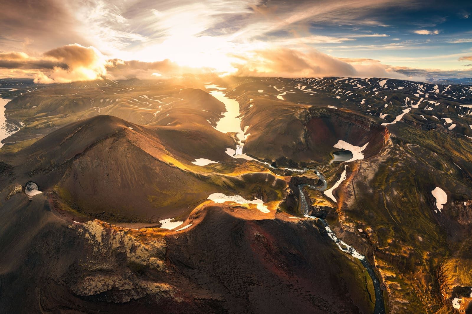 Aerial view of Rauðibotn and the Torfajökull area with volcanic ridges, snow patches, and sunset light.