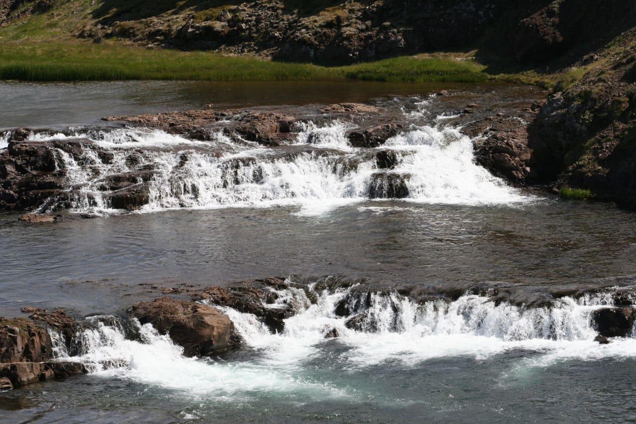 Close view of layered rock ledges and white water at Tröllafossar in Fossatún.