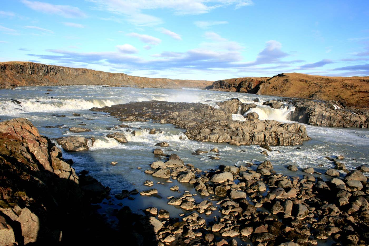 Urriðafoss waterfall viewed across rocky river channels under a clear South Iceland sky.
