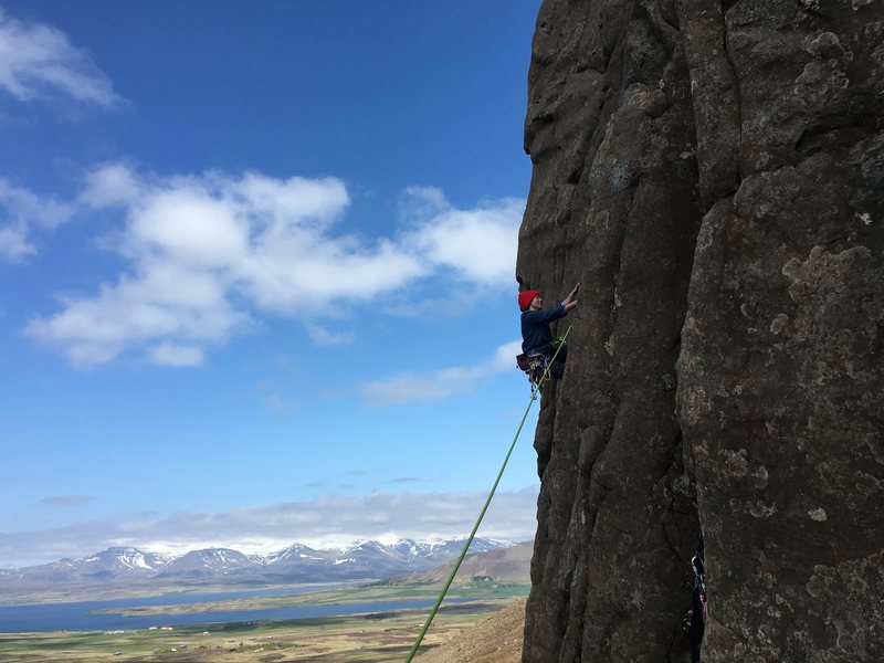 A roped climber on Valshamar with the Hvalfjörður countryside below.