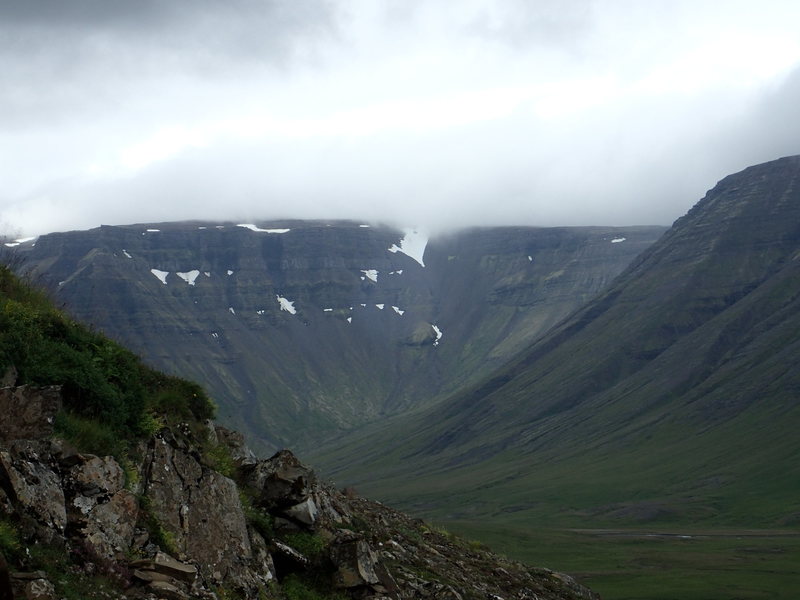 Steep green slopes and low cloud in Eilífsdalur near the Valshamar crag.