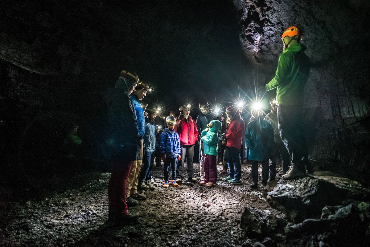 Guide speaking to visitors with headlamps inside Víðgelmir lava cave.