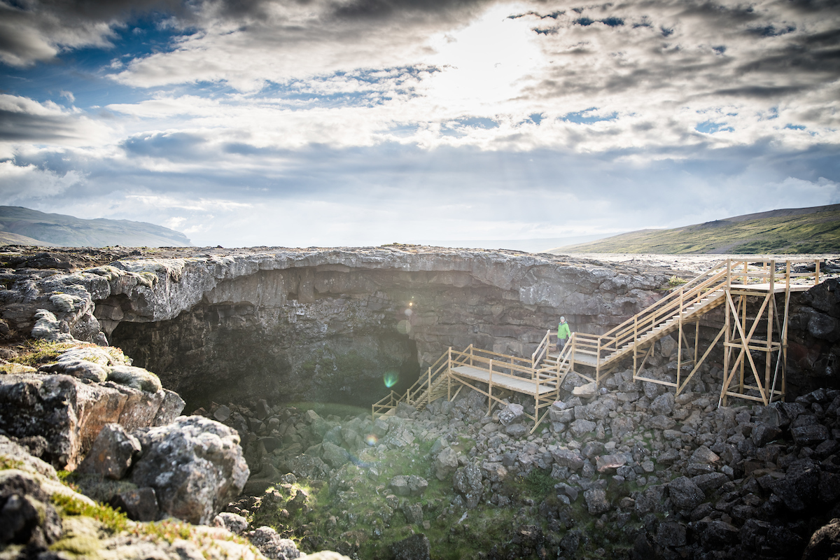 Exterior wooden stairs descending into the entrance of Víðgelmir lava cave.