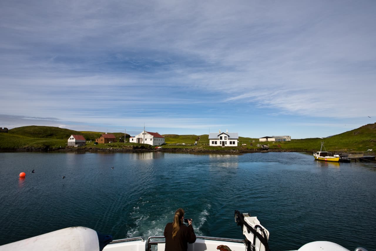 Vigur Island farm buildings and harbor seen from a boat in Ísafjarðardjúp.