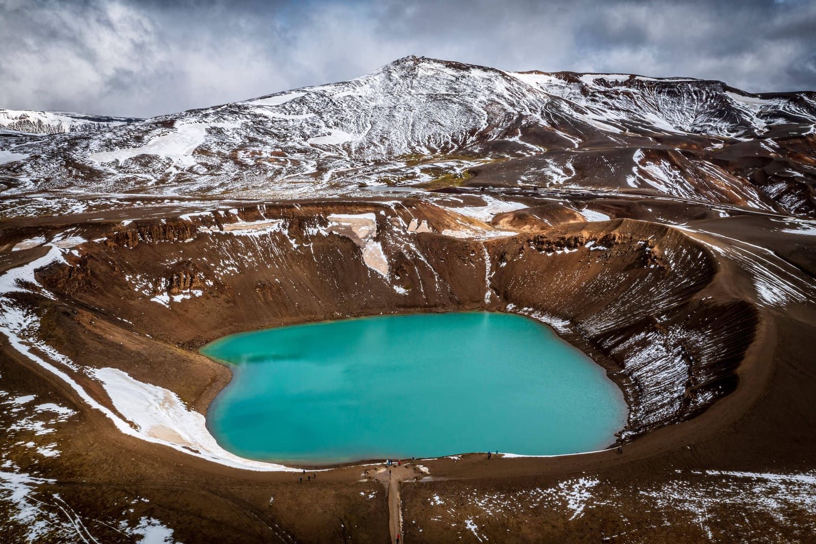 Aerial view of Víti crater, snow patches, roads, and Krafla volcanic terrain in North Iceland.