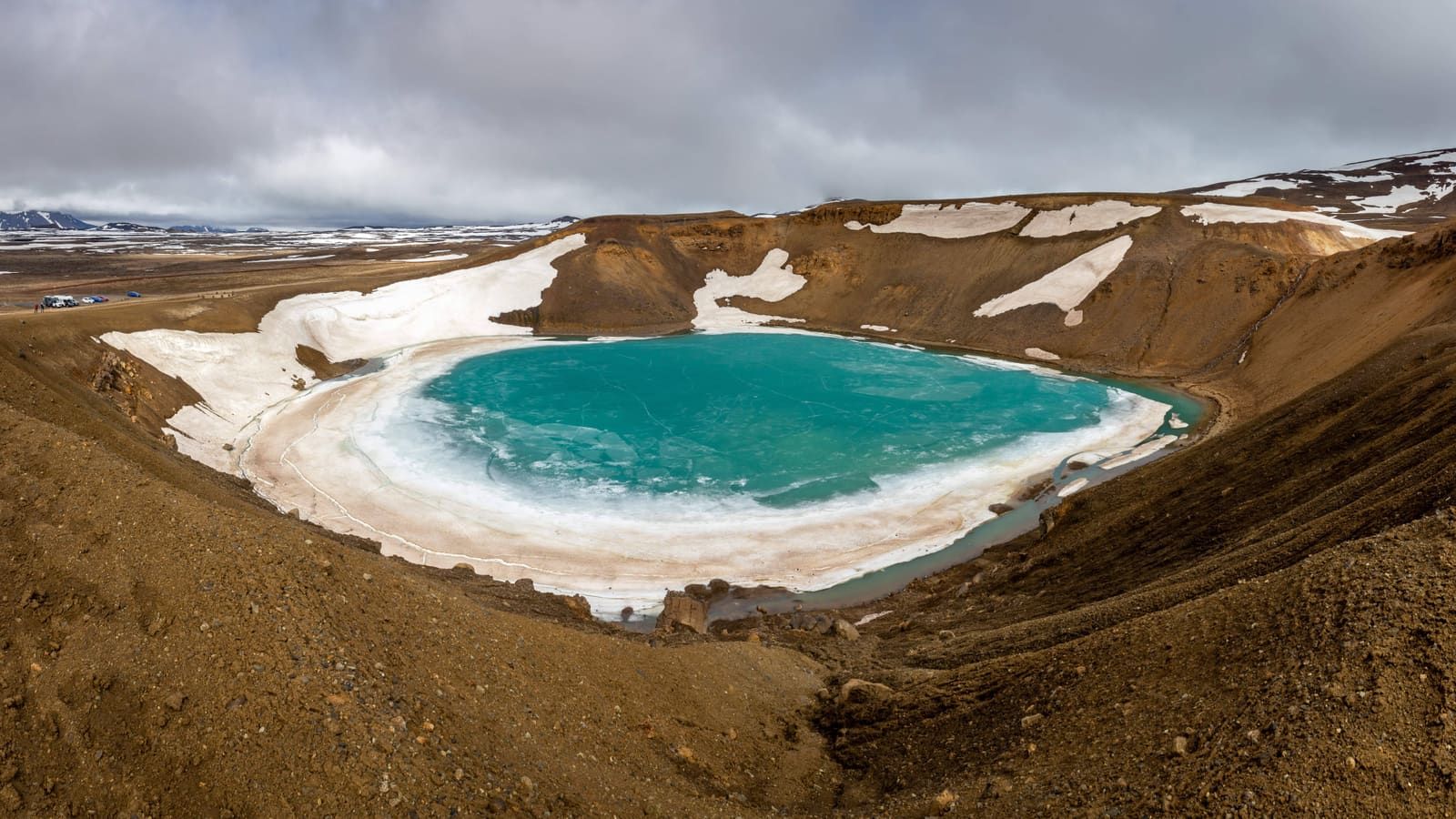 Víti crater lake at Krafla under cloud with snow patches on the volcanic rim.