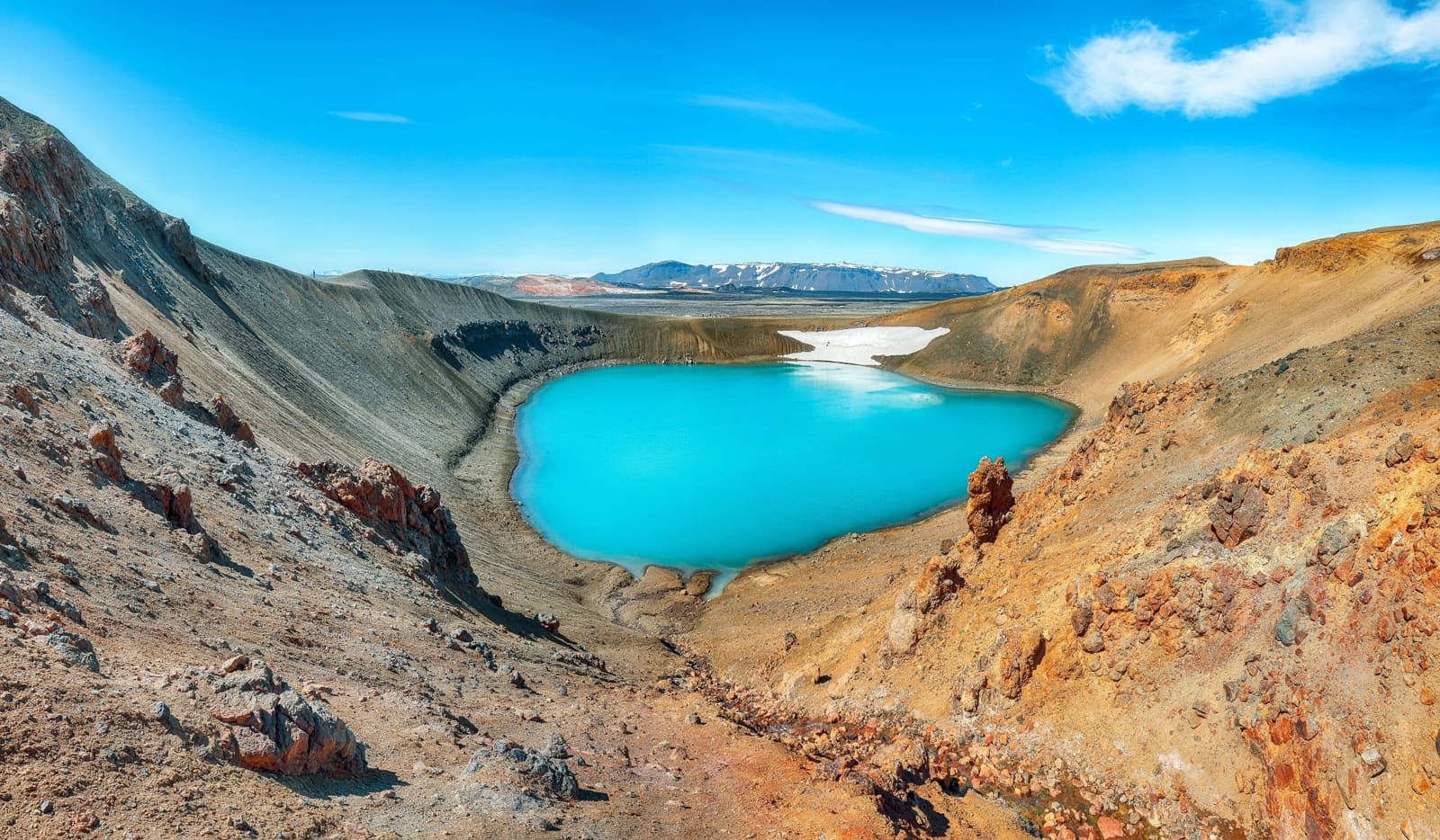 Reddish volcanic slopes around the turquoise water of Víti crater at Krafla.
