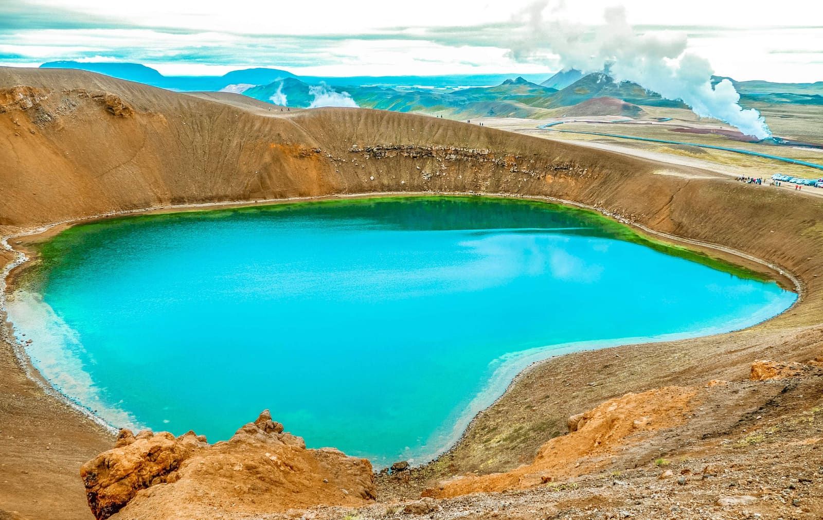 Steam rising beyond the blue-green lake inside Víti crater in the Krafla area.