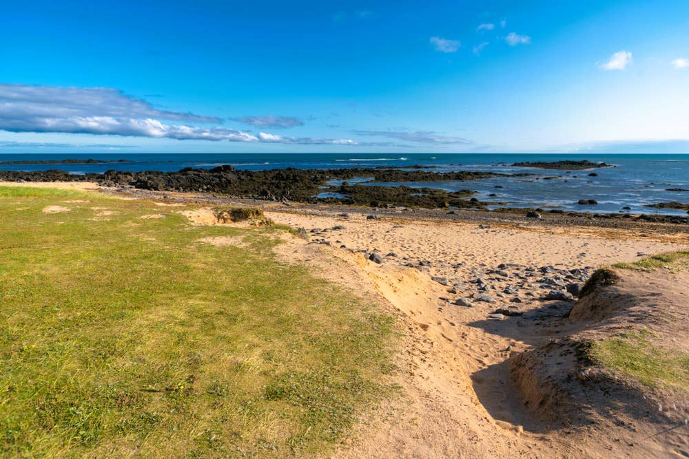 Golden sand, dark rocks, and tide pools along the shore at Ytri Tunga Beach.